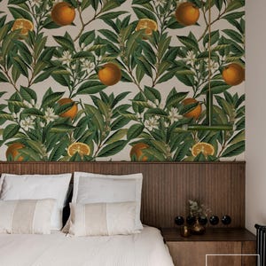 May include: Bedroom with a headboard and a wallpaper featuring a botanical orange tree design. The wallpaper has green leaves, orange fruits, and white flowers. The bed has white pillows and a light green blanket. A wooden nightstand is on the right.