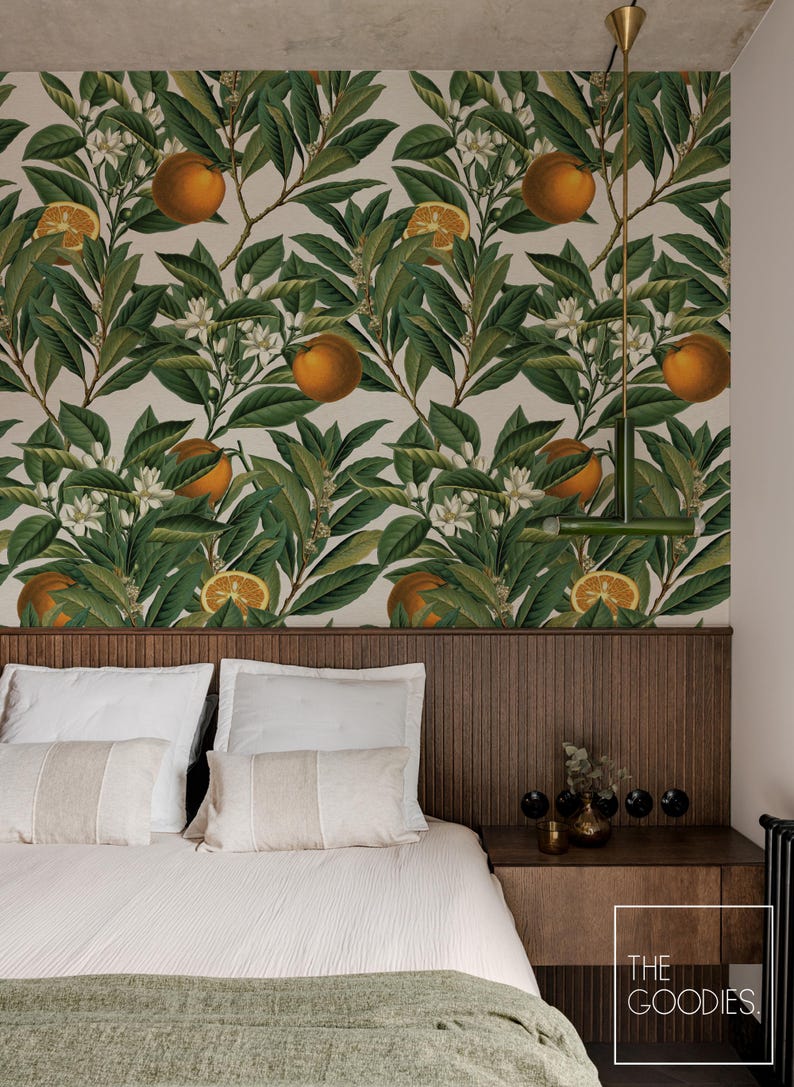 May include: Bedroom with a headboard and a wallpaper featuring a botanical orange tree design. The wallpaper has green leaves, orange fruits, and white flowers. The bed has white pillows and a light green blanket. A wooden nightstand is on the right.