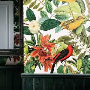 May include: A white background with a floral pattern featuring red, pink, and white flowers. A black and red bird is perched on a branch with green leaves. The background is a white wallpaper with a floral pattern.