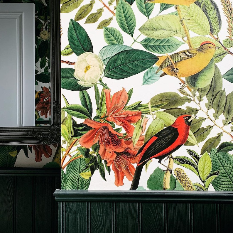 May include: A white background with a floral pattern featuring red, pink, and white flowers. A black and red bird is perched on a branch with green leaves. The background is a white wallpaper with a floral pattern.