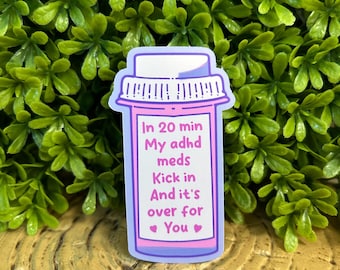 May include: A sticker in the shape of a prescription pill bottle with the text "In 20 min My adhd meds Kick in And it's over for You" in pink and purple. The sticker has a white background and is surrounded by green foliage.