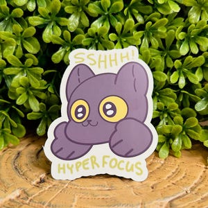 May include: Purple cat sticker with yellow eyes and the text "SSHHH! HYPER FOCUS" in yellow.