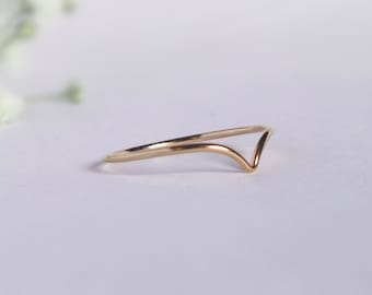 Puede incluir: Un anillo de oro simple con un diseño en forma de V. El anillo está hecho de una banda delgada de metal y es de estilo minimalista.