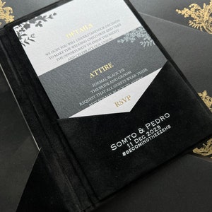 May include: Black and white wedding invitation with gold accents. The invitation features a floral design and the text "Details", "Attire", "RSVP", "Somto & Pedro", "11 Dec 2023", and "#BecomingTheezehs".