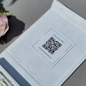 Puede incluir: Una tarjeta blanca con un c&oacute;digo QR y el texto "Por favor, escanea para RSVP" y "www.samuelandfienella.com".
