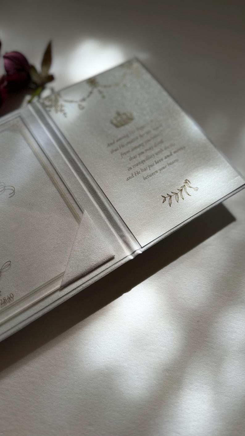 May include: A white invitation card with a gold design and text that reads "And he shall send his angel before you to guard you on your way and to bring you to the place that I have prepared for you. In tranquility you will enter and he has put love and mercy between you and your heart."