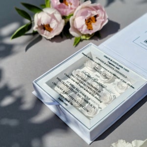 Puede incluir: Caja de invitaci&oacute;n de boda blanca con una ventana transparente que muestra una tarjeta de invitaci&oacute;n blanca con el texto "Request the honor of your presence at the marriage of their children Simon & Svetlana Vays Together with Edward & Renata Gershfeld Fenella Vays AND Samud Gershfeld Saturday, December 10 Two Thousand Twenty Two Cocktail hour will begin at five in the evening ST. Regis Bal Harbour Arbour 9703 Collins Avenue, Bal Harbour, FL Ceremony & Reception to Follow Attire: Black Tie Adults only"