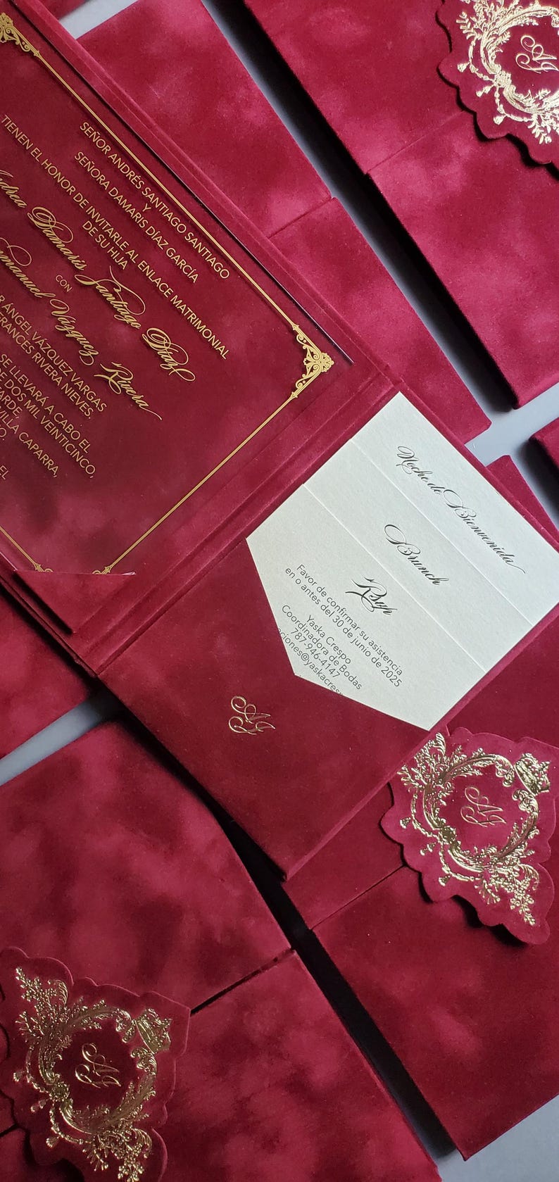 May include: Burgundy wedding invitations with gold foil accents. The invitations feature elegant script and decorative embellishments. The design includes a pocket-style invitation with inserts and a matching enclosure card.