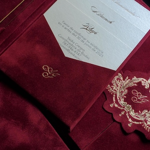 May include: Burgundy velvet wedding invitation suite with gold foil details. The invitation includes the names of the couple, event details, and a request to RSVP by June 30, 2025. The suite includes a decorative tag.