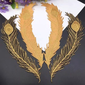Puede incluir: Tres parches de bordado de plumas de pavo real doradas. Las plumas están detalladas con un contorno dorado y un ojo dorado en la parte superior.