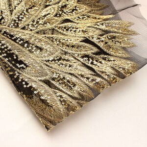 May include: Gold sequined fabric with a black mesh backing. The sequins are arranged in a feather pattern.