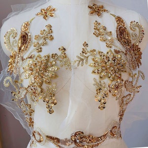 May include: Gold beaded and sequined applique featuring a bird and floral design. The applique is on a sheer mesh fabric.