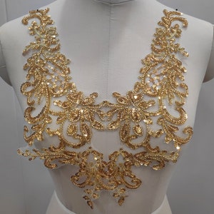 以下が含まれることがあります： 花柄のゴールドのビーズレースアップリケ。アップリケは、どんな衣服にも輝きを加えるのに最適です。