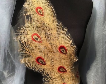 May include: Gold and red peacock feather embroidery applique. The applique features a design of several peacock feathers with red eyes and gold glitter.