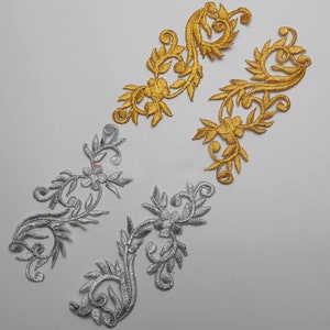 Puede incluir: Dos juegos de apliques florales bordados en oro y plata. Los apliques tienen forma de enredaderas con hojas y flores.