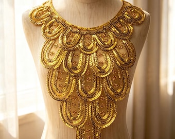 May include: A gold sequin collar applique featuring a layered, scalloped design with small floral accents. The piece is constructed with rows of metallic gold sequins arranged in a repeating U-shape pattern, creating a decorative neck piece.
