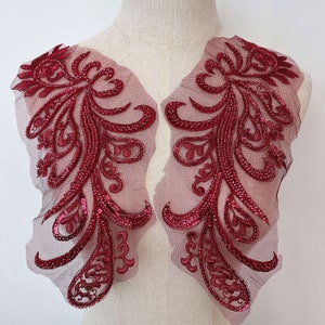 Può includere: Due applicazioni in pizzo con paillettes color borgogna con un motivo paisley. Le applicazioni sono su un tessuto di rete trasparente.