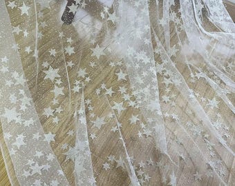 May include: White tulle fabric with silver glitter stars. The fabric is sheer and has a delicate texture.
