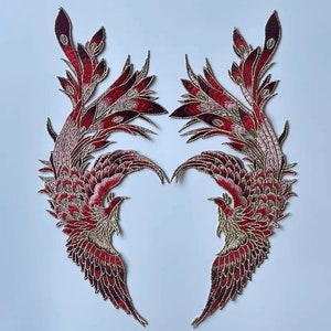 May include: Two red and gold embroidered phoenix bird appliques. The birds are facing each other with their wings spread out. The appliques are perfect for adding a touch of elegance to any project.