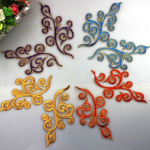 Puede incluir: Cinco parches bordados para planchar en diferentes colores. Los parches tienen la forma de un diseño floral estilizado con hilo dorado que delinea los bordes. Los colores de los parches son dorado, morado, azul, rojo y dorado.