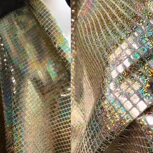 May include: Close-up of shimmering fabric with a grid pattern. The fabric has a gold base with iridescent squares that reflect multiple colours. The material is draped, showing the texture and light reflection.