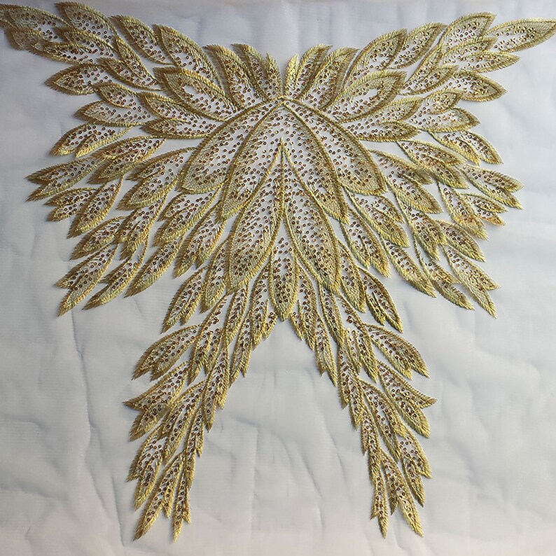 May include: Gold embroidered applique with a feather design. The applique is made of a sheer fabric with gold thread and sequins.