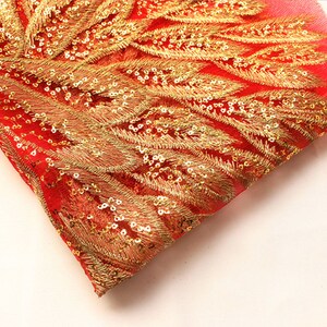 May include: Red mesh fabric with gold embroidered feather designs and sequins.