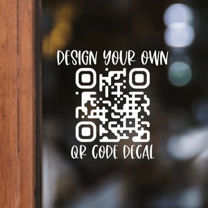 May include: White QR code decal on a glass door. The text "DESIGN YOUR OWN" is above the QR code, and "QR CODE DECAL" is below it. The decal is against a blurred background with a wooden door frame on the left.