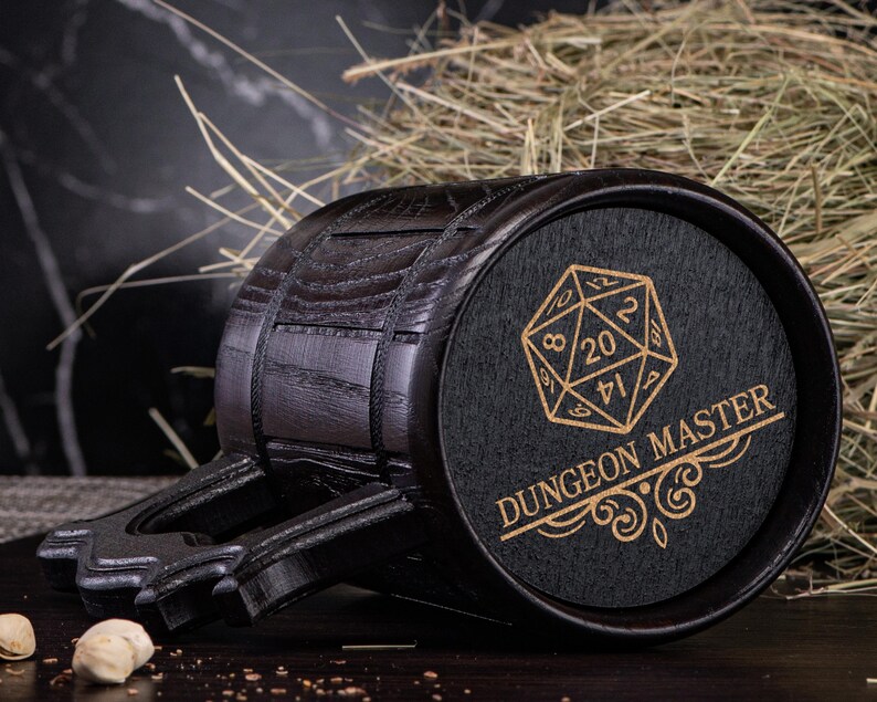May include: Black wooden beer stein with a handle and a black and gold design of a 20-sided die and the text "Dungeon Master".