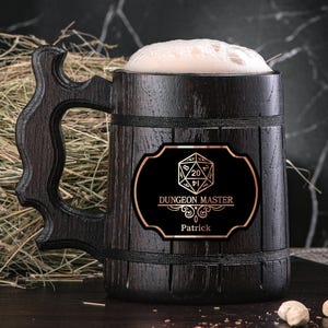 May include: A dark brown wooden beer stein with a black label that says "Dungeon Master" and features a 20-sided die. The label also includes the name "Patrick".