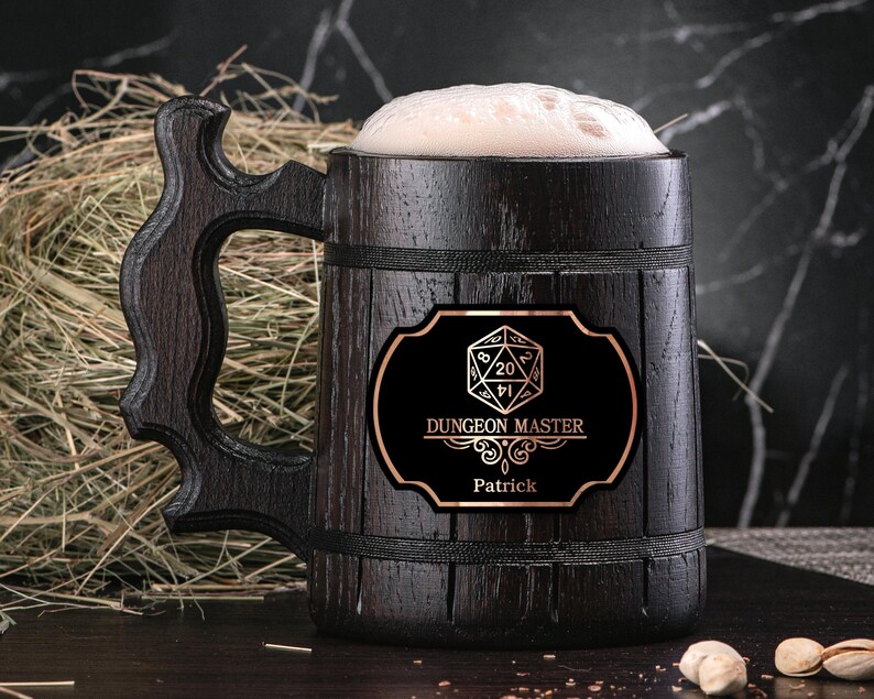 May include: A dark brown wooden beer stein with a black label that says "Dungeon Master" and features a 20-sided die. The label also includes the name "Patrick".