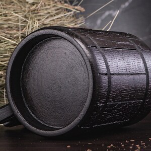 Puede incluir: Un jarro de madera negro en forma de barril con asa. El jarro tiene una superficie texturizada y est&aacute; hecho de madera oscura. El jarro est&aacute; dise&ntilde;ado para contener l&iacute;quidos y tiene una capacidad de aproximadamente 473 ml.