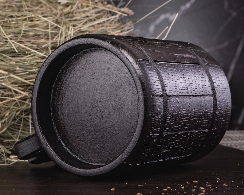 Puede incluir: Un jarro de madera negro en forma de barril con asa. El jarro tiene una superficie texturizada y est&aacute; hecho de madera oscura. El jarro est&aacute; dise&ntilde;ado para contener l&iacute;quidos y tiene una capacidad de aproximadamente 473 ml.