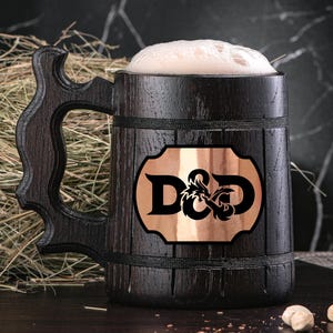May include: A dark wooden beer stein with a handle, filled with beer and foam. The stein features a copper plaque with "D&D" and a dragon graphic. The stein is on a dark surface.