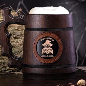 May include: A dark brown wooden beer stein with a black leather patch that says "Dungeon Master" and features a cartoon image of a Dungeon Master with a 20-sided die.