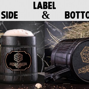 May include: A dark brown wooden beer stein with a black label that says "Dungeon Master" and features a gold 20-sided die. The stein has a handle and is sitting on a bed of straw.