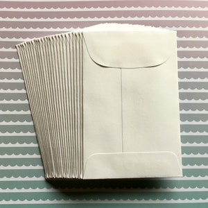 以下が含まれることがあります： 上部にフラップが付いた白い封筒の束。封筒はすべてきれいに整列しており、郵送に使用できる状態です。