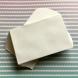 以下が含まれることがあります： 模様のある背景の上に白い封筒が積み重ねられています。封筒は扇形に配置されており、一番上の封筒が他の封筒を覆っています。