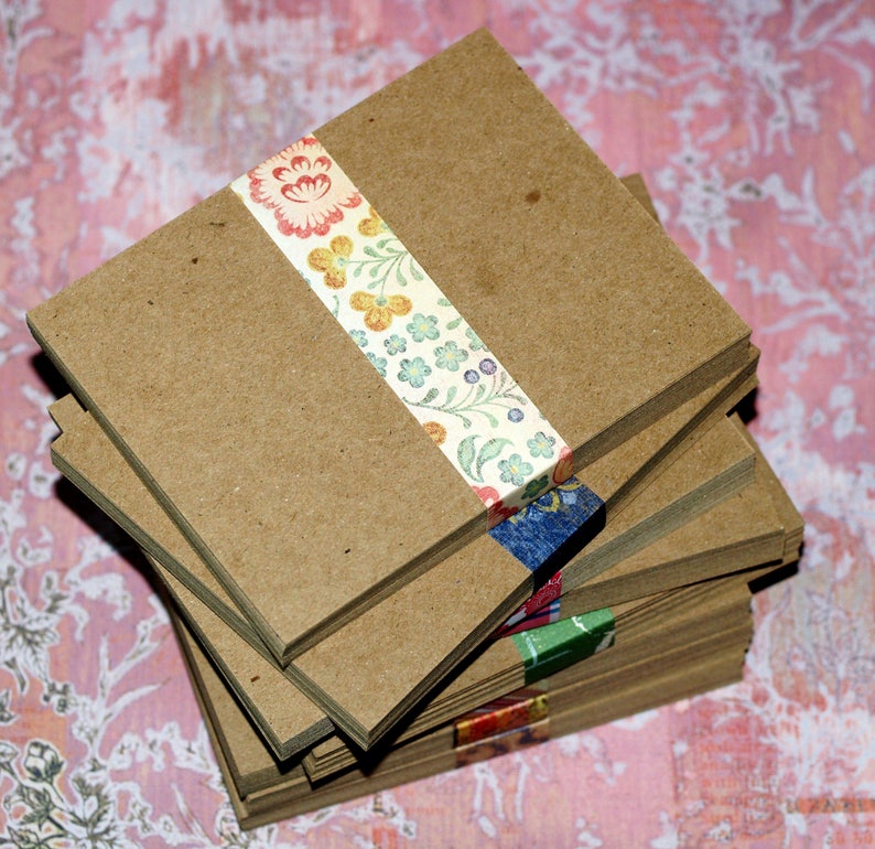 May include: A stack of brown cardstock paper with a floral patterned washi tape wrapped around the top. The paper is perfect for crafting and scrapbooking.