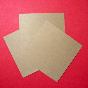 May include: Three brown paper squares stacked on top of each other against a red background.