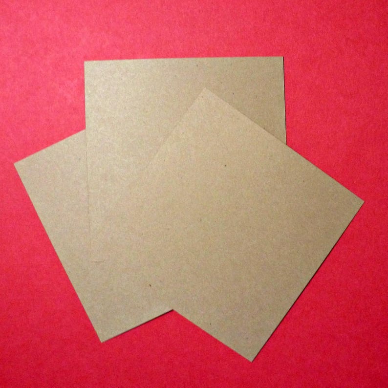 May include: Three brown paper squares stacked on top of each other against a red background.