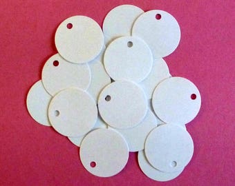 May include: A pile of white round paper gift tags with a hole punched in the top. The tags are arranged in a random pattern on a pink background.