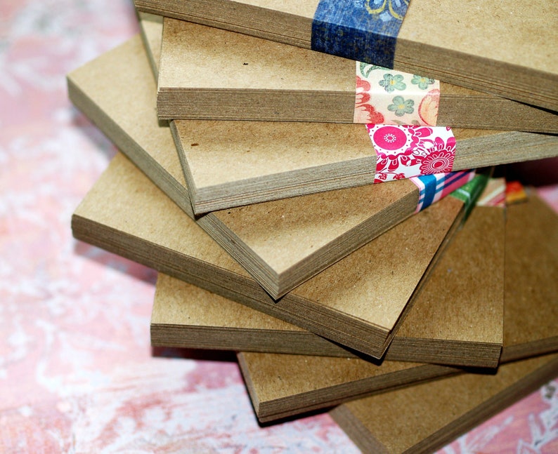May include: A stack of brown cardstock paper with decorative patterned washi tape. The paper is stacked in a spiral pattern.