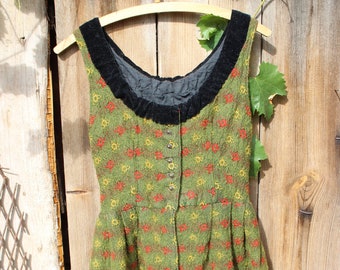 May include: A green and red floral patterned dress with a black velvet neckline. The dress is hanging on a wooden hanger against a wooden background.