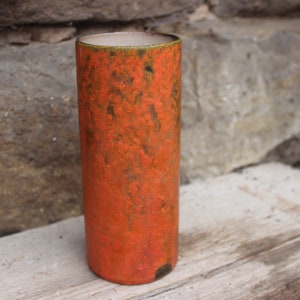 Può includere: Vaso in ceramica arancione con superficie testurizzata. Il vaso è cilindrico e ha una parte superiore leggermente svasata.
