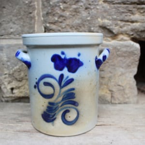Peut inclure: Un pot en céramique blanche avec des motifs floraux bleus et deux anses. Le pot a un couvercle et est décoré d'une fleur bleue et de feuilles.