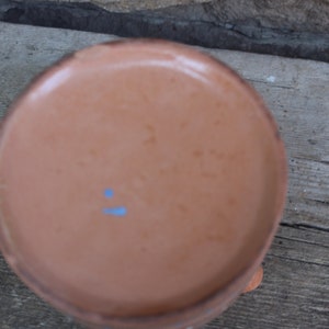 May include: The underside of a terracotta pot with a light blue mark.
