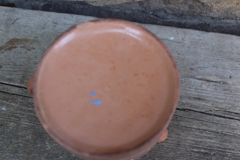 May include: The underside of a terracotta pot with a light blue mark.