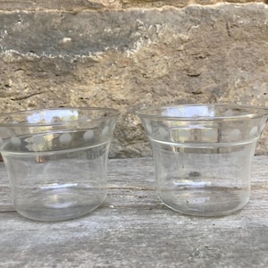 May include: Two clear glass bowls with a flared rim and a subtle white polka dot pattern encircling the upper portion of each vessel. The bowls feature a smooth, transparent finish and a wide, open top design suitable for serving various items.