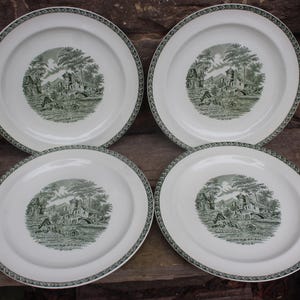 May include: Set of four white ceramic plates with green trim and a green and white design of a house and trees.